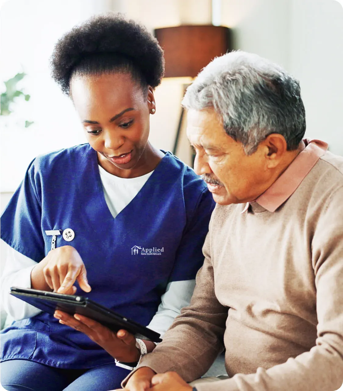 nurse and elderly man staring on a tablet screen